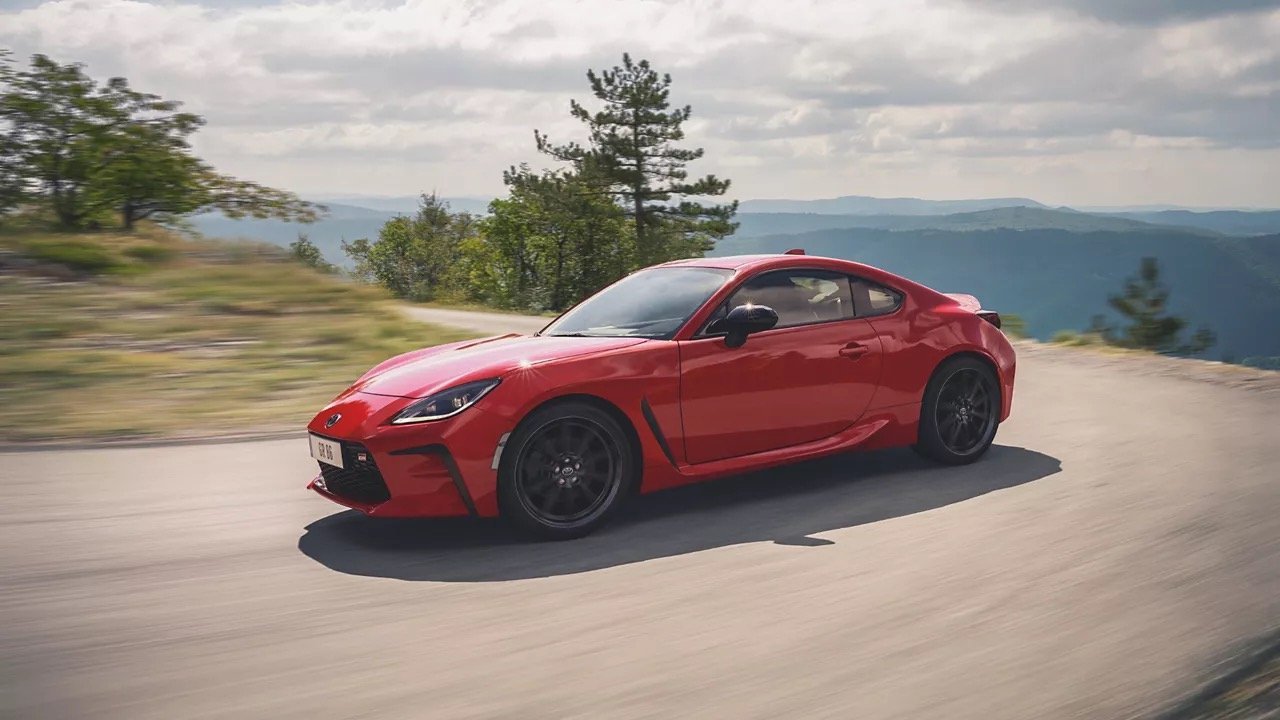 Red sports car driving along a hillside road