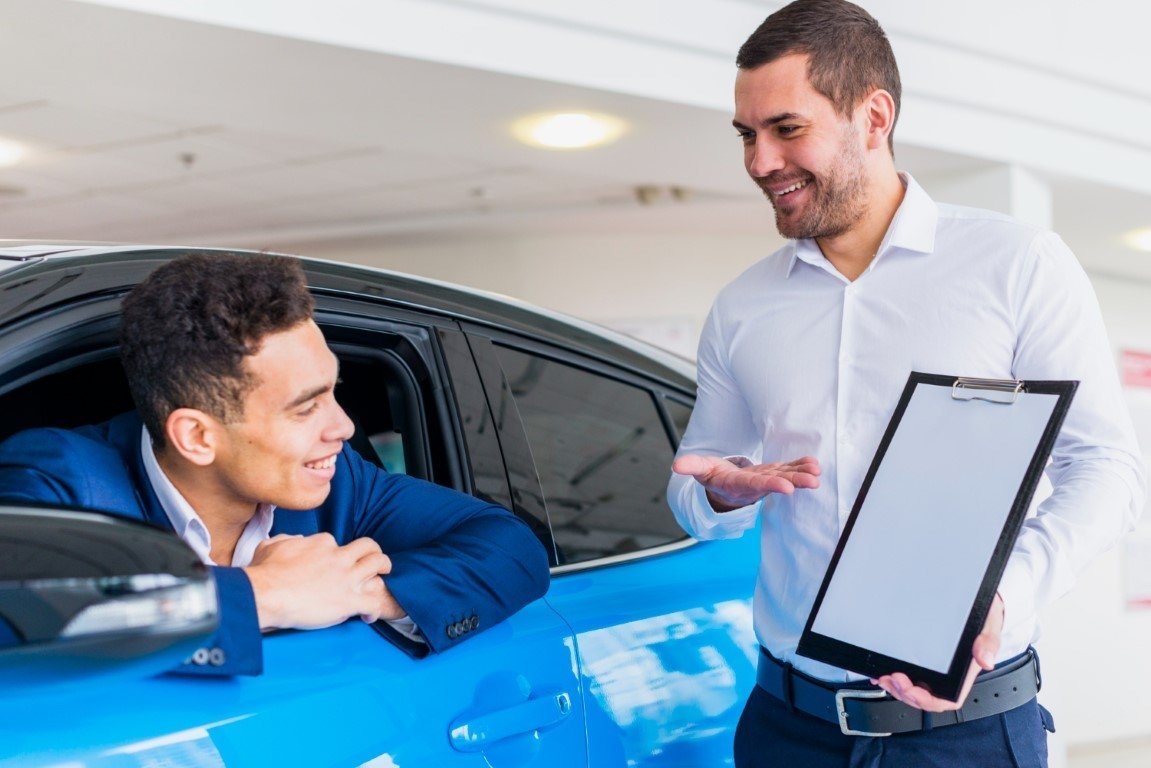 Salesman showing a tablet to a customer sitting in a car