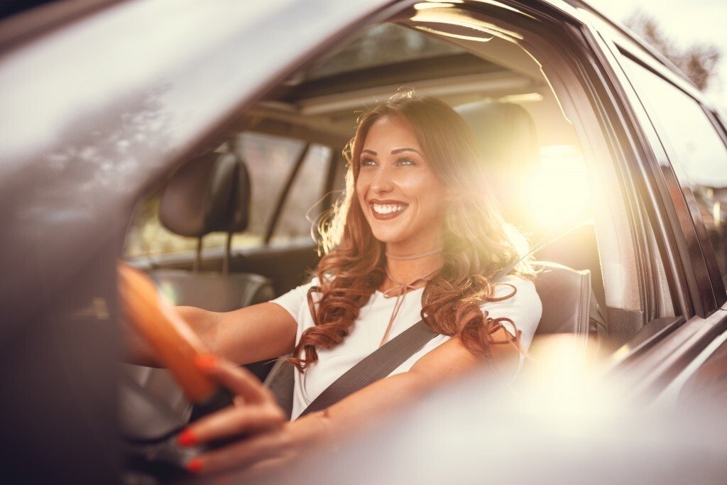 Smiling driver behind the wheel of a car in warm evening light