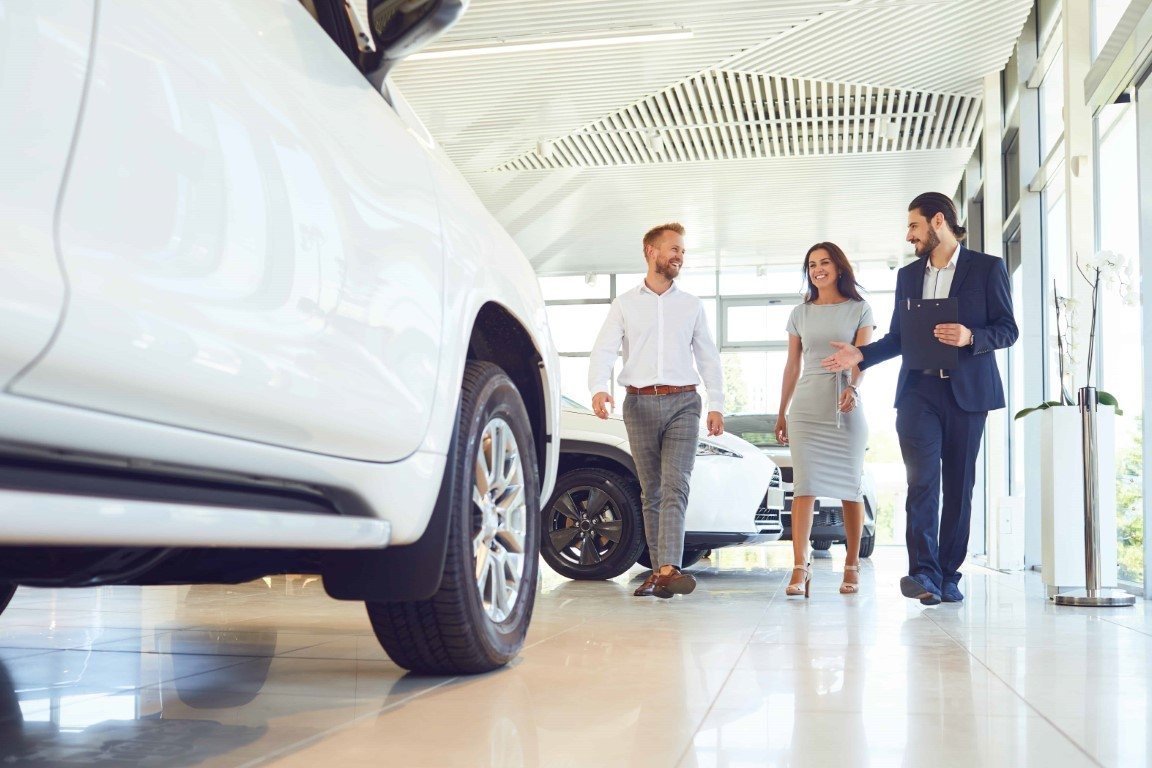 Sales staff welcoming customers into a car dealership showroom